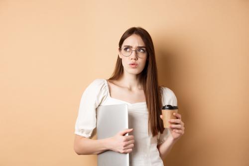 Confused woman holding a coffee and laptop